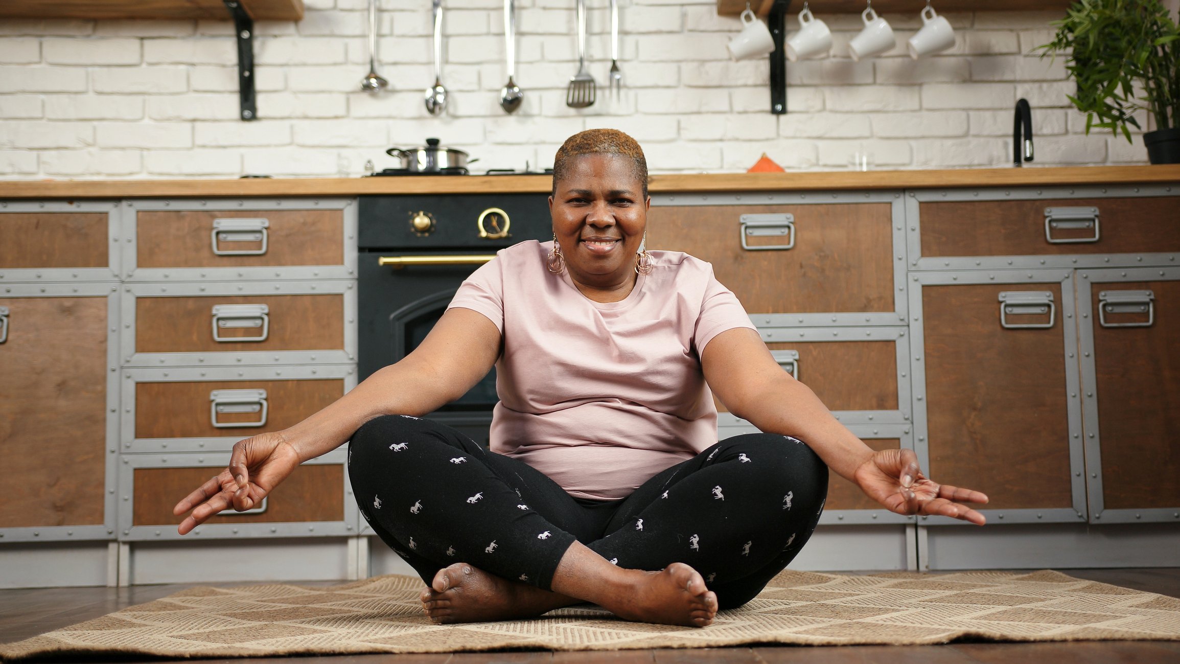 Person in yoga pose on floor in kitchen.