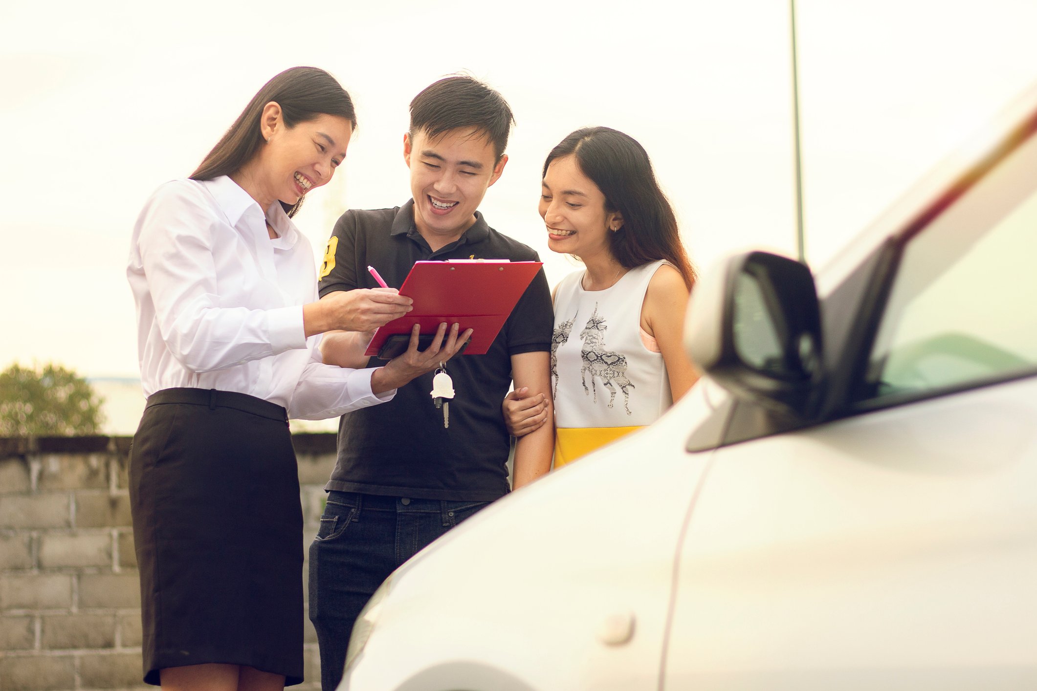 An Asian couple completing the purchase of a car.