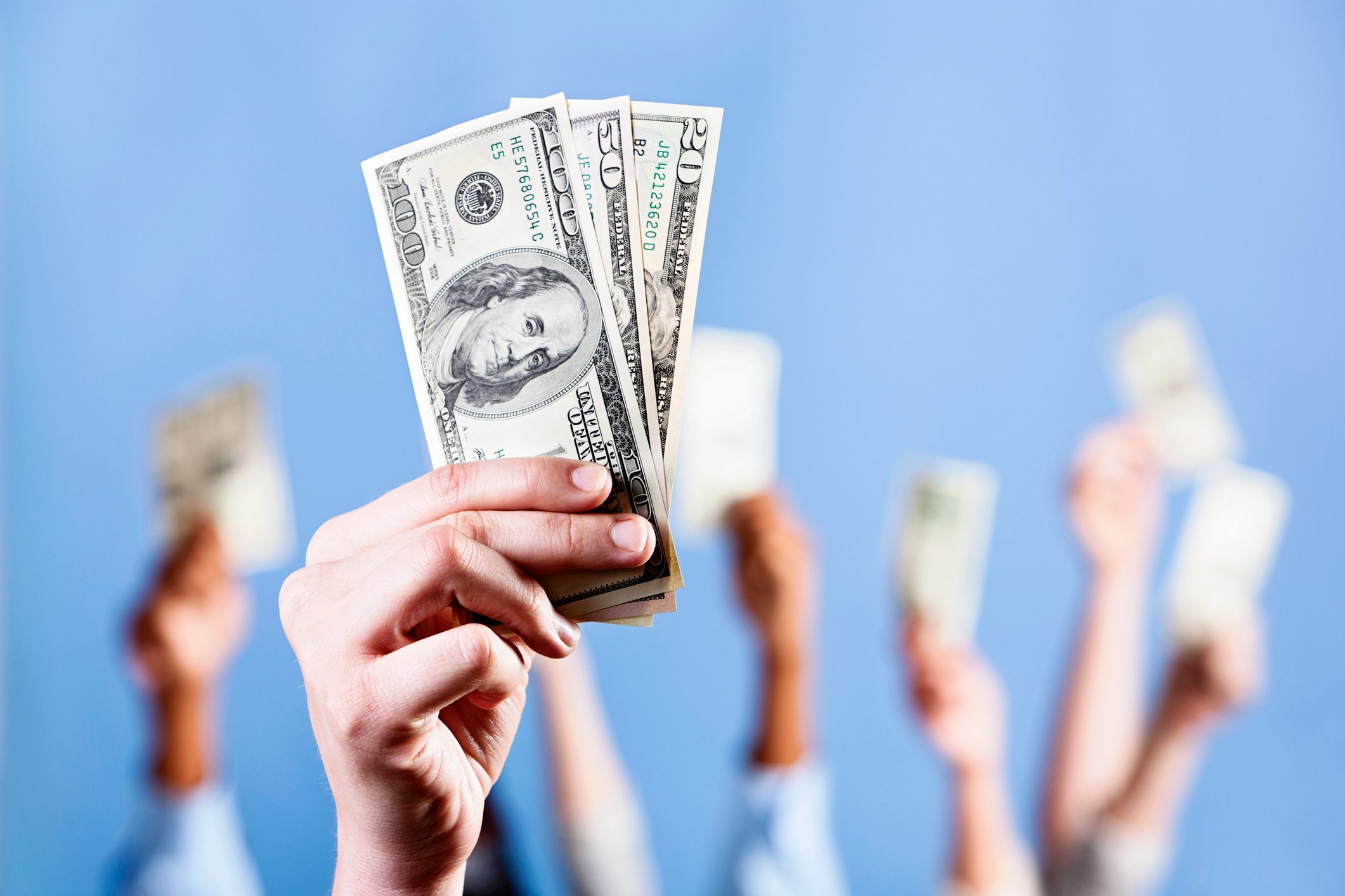 Several hands raised with cash in them.