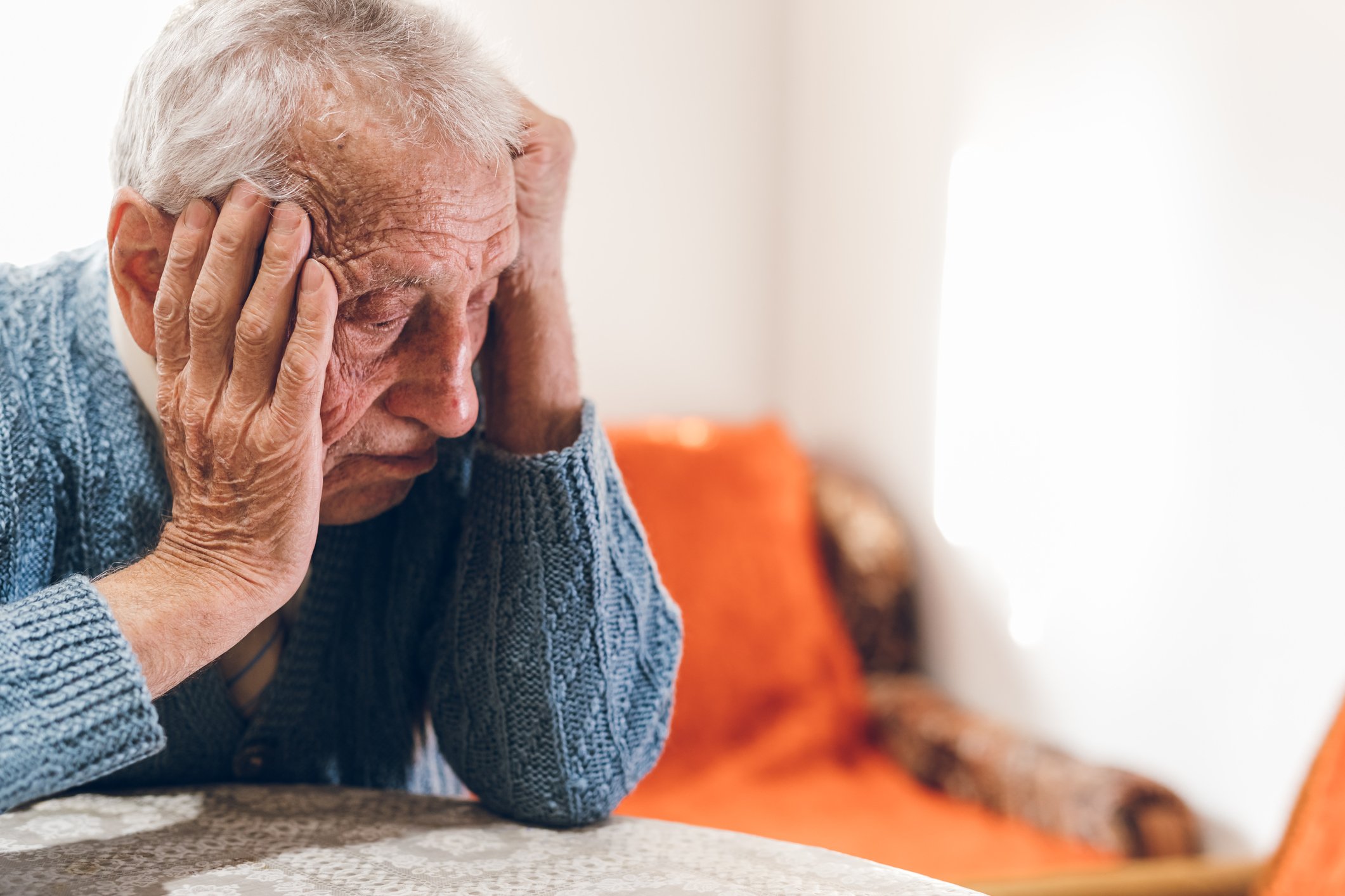 A senior sitting at a table with a sad look on his face.