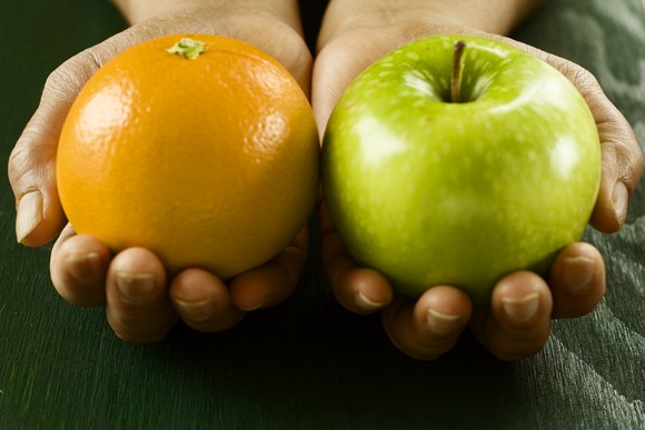 Hands holding an orange and an apple.