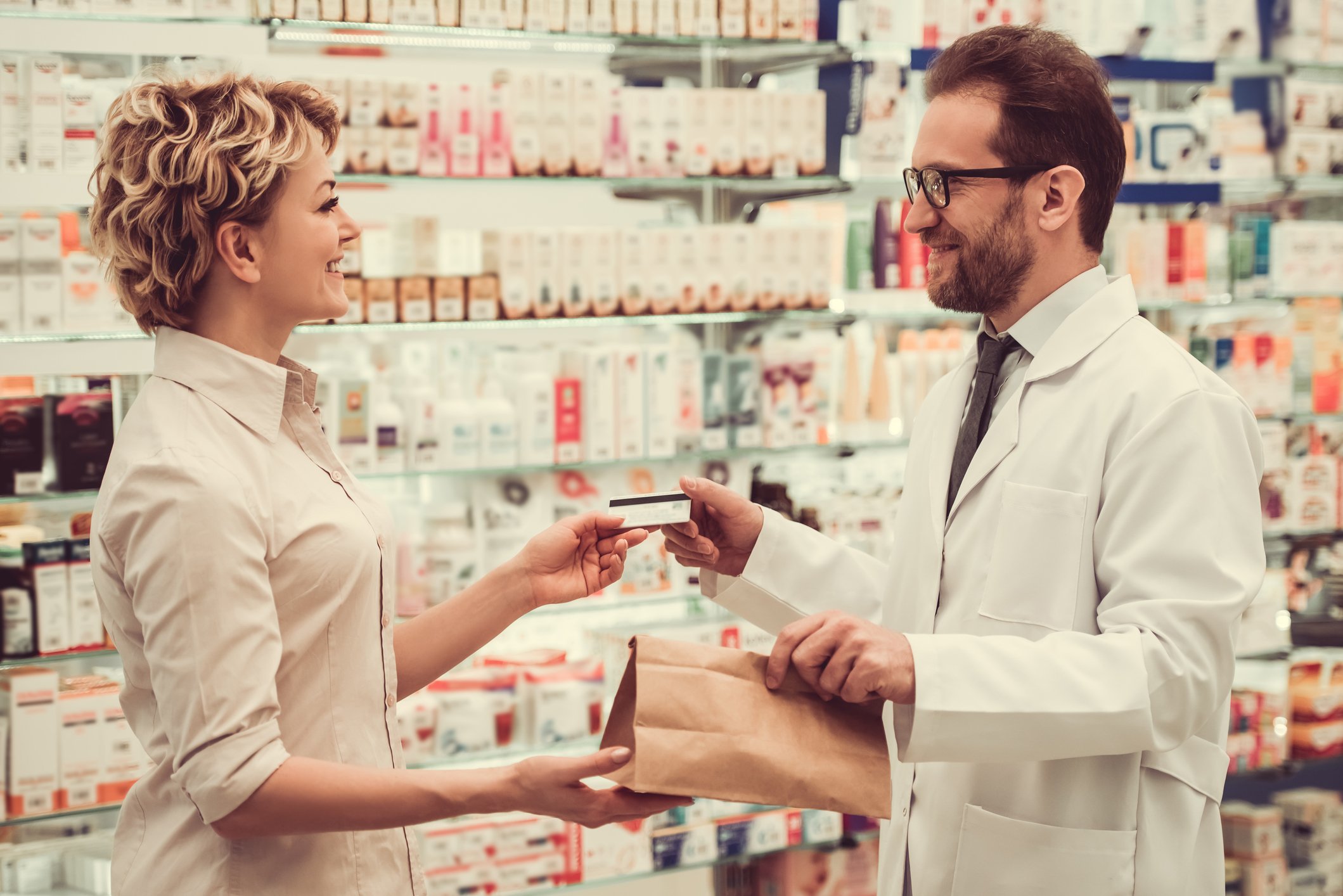 A pharmacist gives a customer their prescriptions in a drug store.
