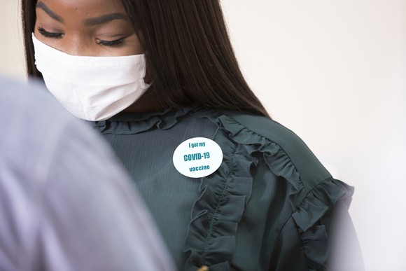 A masked person wearing an "I got my COVID-19 vaccine" badge.