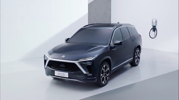 Dark blue Nio ES8 electric SUV in front of battery charger. 