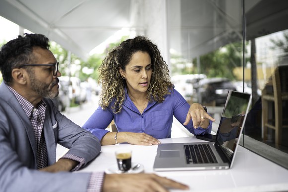 two business people looking at data on computer screen