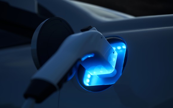 A charger in an EV port glows blue. 