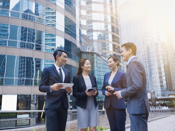 A business team meets in front of a building.