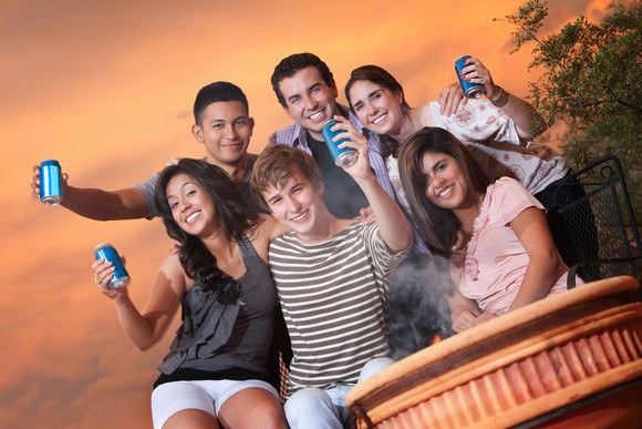 A group of teenagers drinking canned soda.