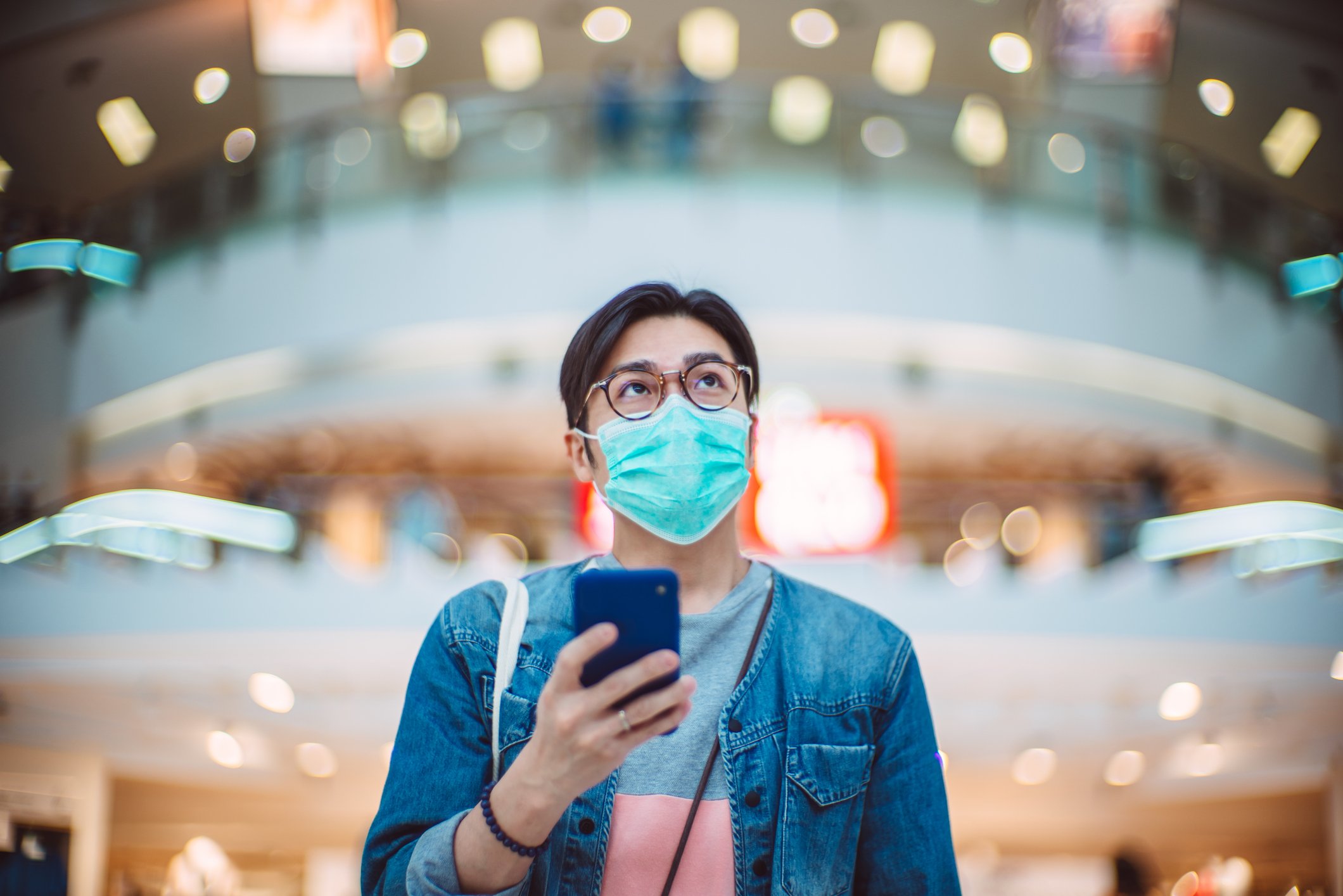 Person in mask using smartphone in public.