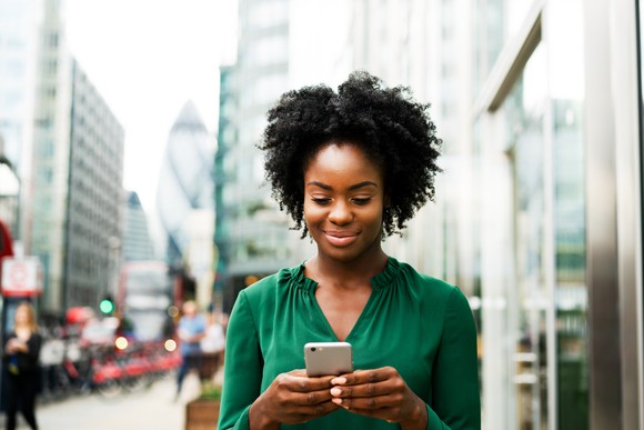 A person checks a smartphone on the street.