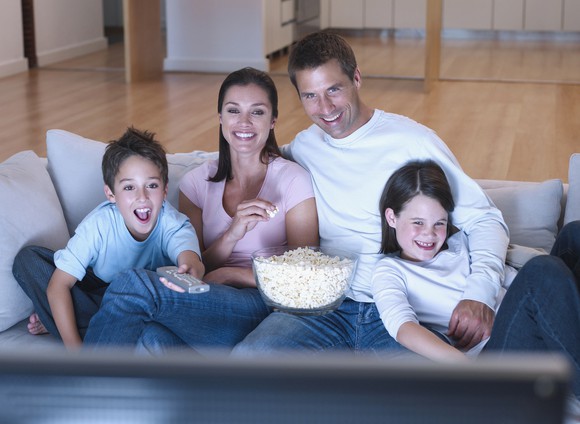 A family eating popcorn and watching television.
