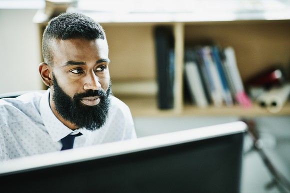 A businessperson sitting at their desk, smiling. 