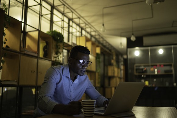 Person in an office looking intently at a laptop screen. 