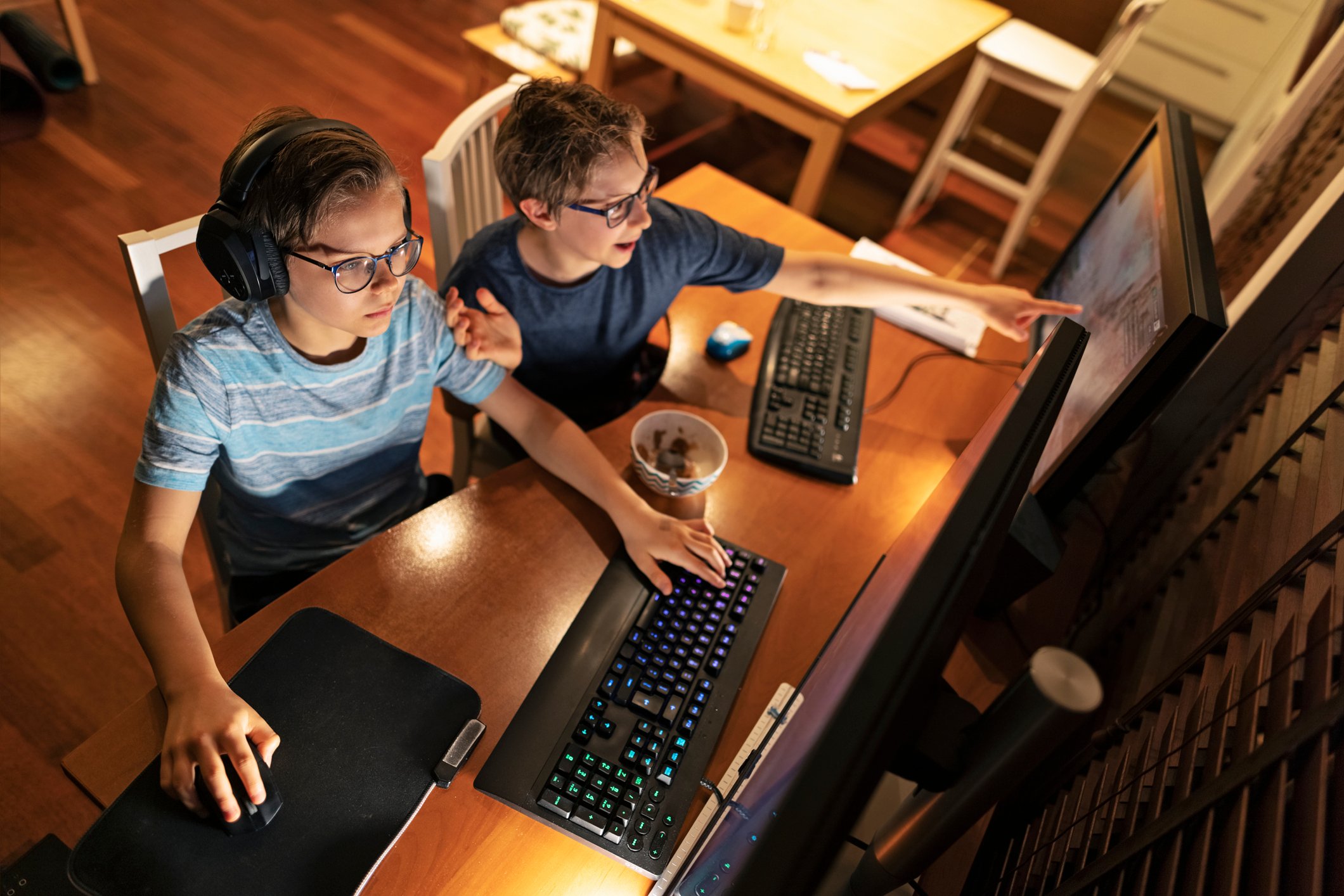 Two kids playing a video game on a personal computer.