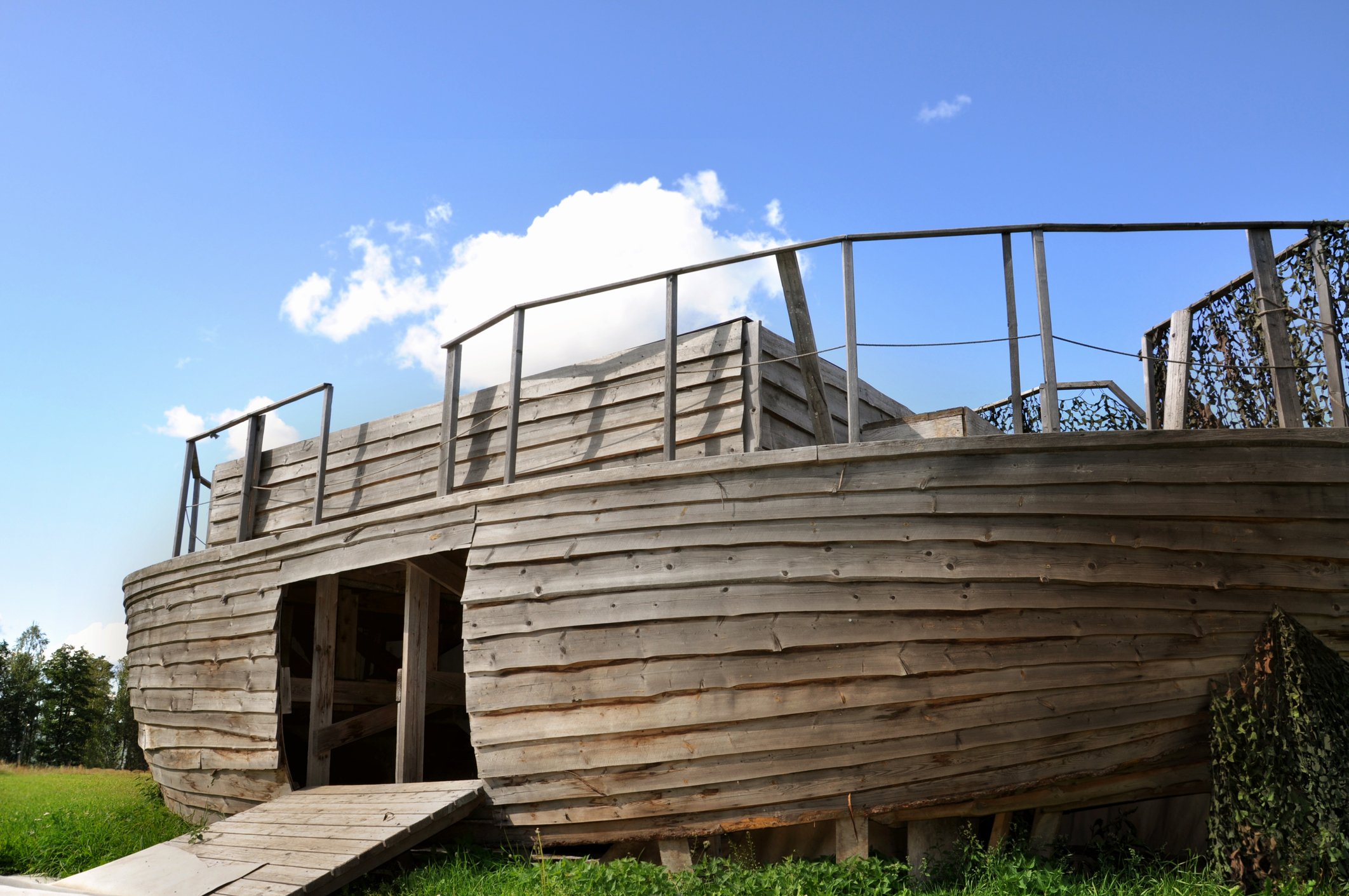A wooden ark with an open door on land.