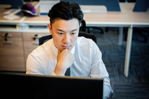 Business man thinking while looking at a computer.