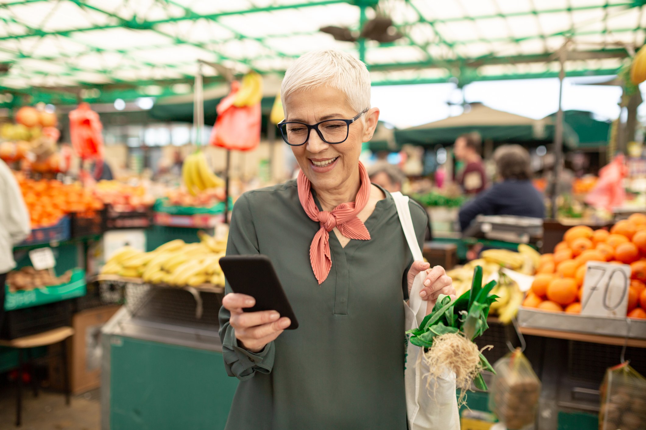 Woman looks at her cell phone in a grocery store. 