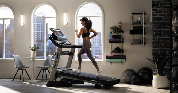 A NordicTrack user running on a treadmill in an apartment.