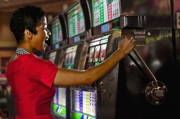 Person pulling handle on slot machine.