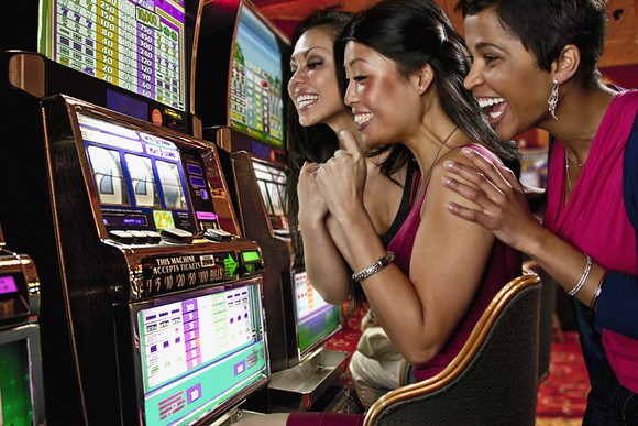 three slot machine players in casino.