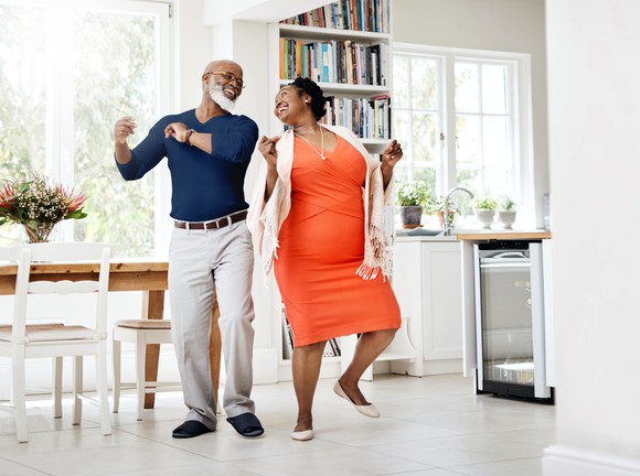 Two seniors dancing in their living room.