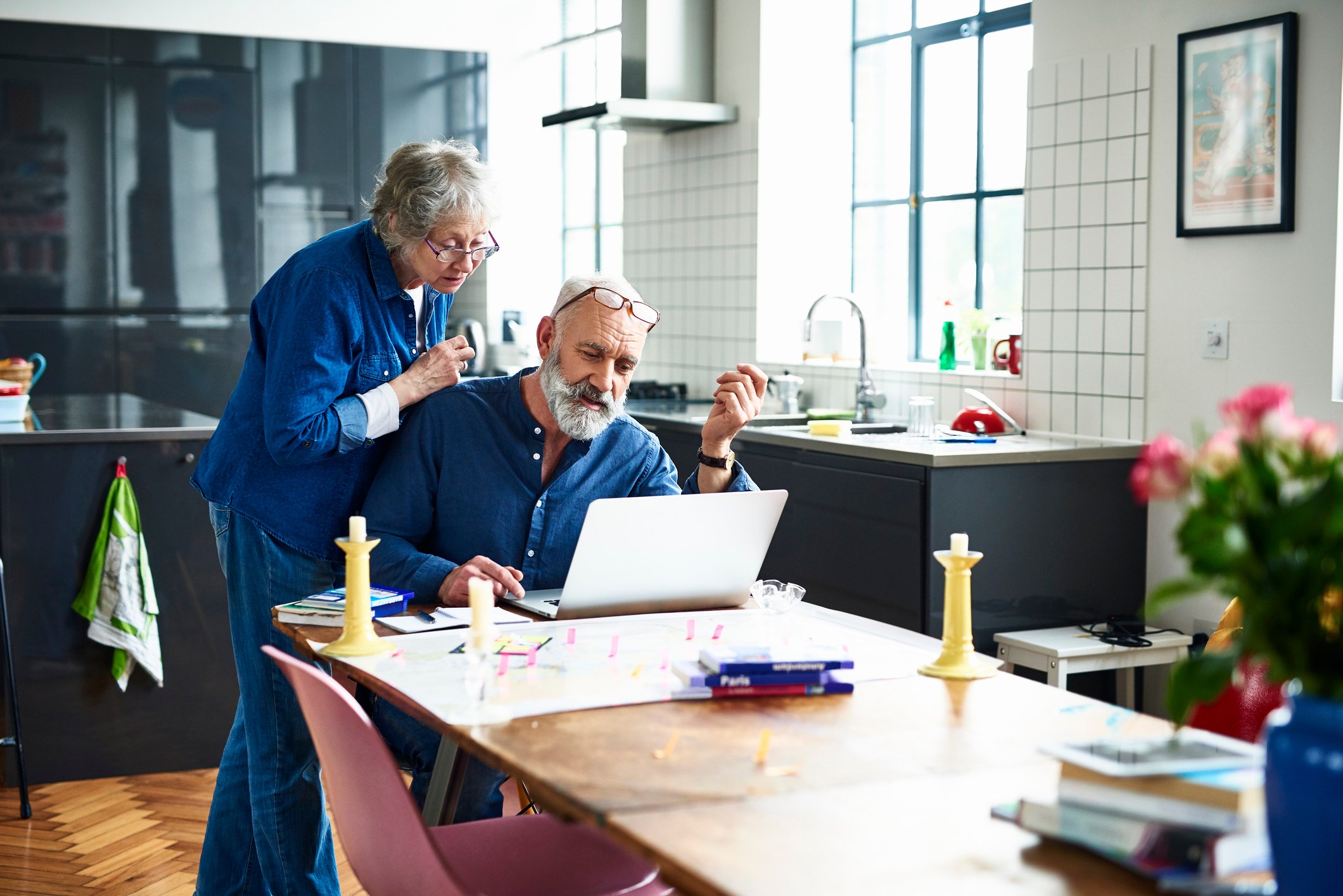 A senior couple looking at a laptop in their kitchen.