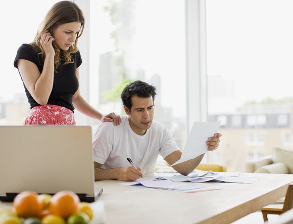 A couple at home looking concerned as they peruse documents. 