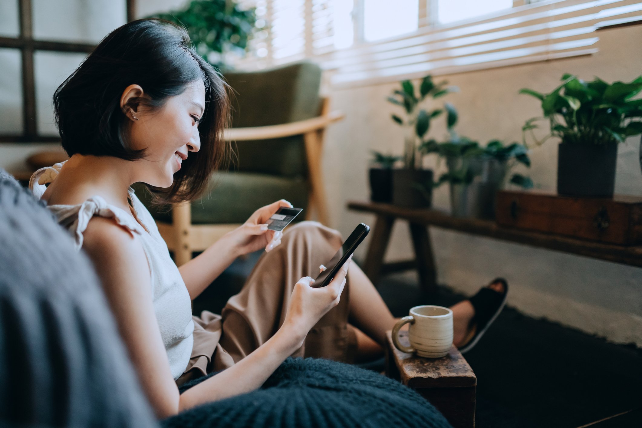 Woman shopping online at home while relaxing with a coffee.