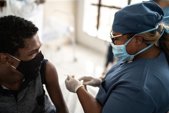Person about to receive a vaccine shot from a healthcare professional.
