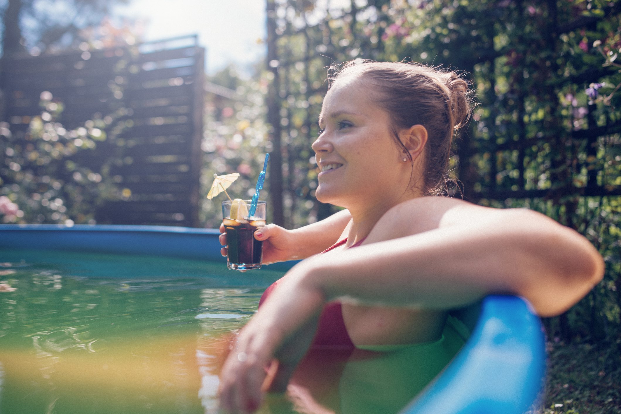 Person holding soda in above-ground hot tub. 