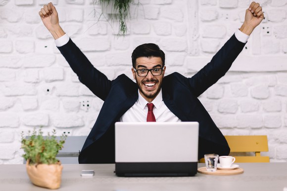 Cheering person sitting in front of laptop.