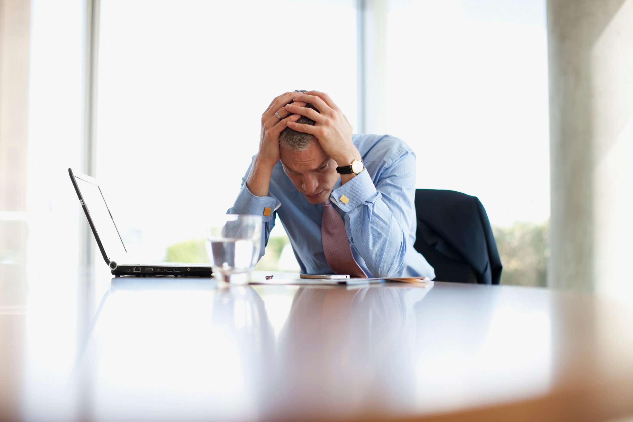 Stressed out investor sitting at a table reviewing his portfolio during a market crash. 