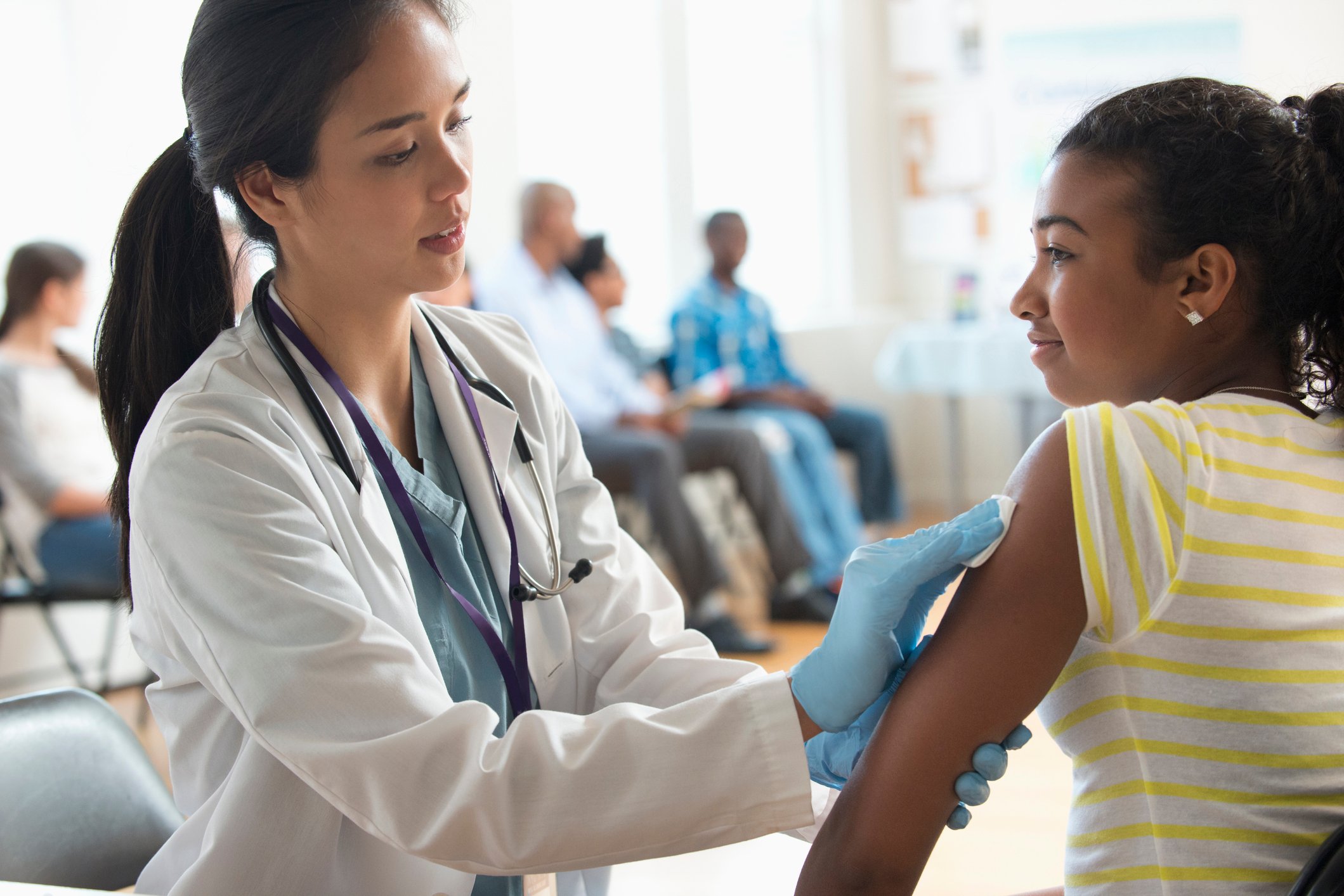 A healthcare worker disinfects a patient's arm prior to giving a vaccine.