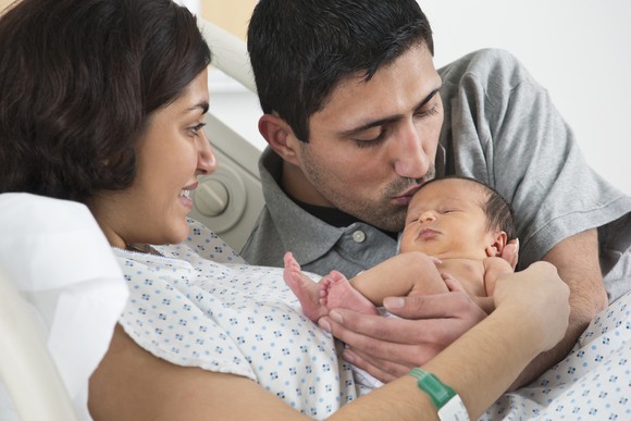 A baby being held by its parents.