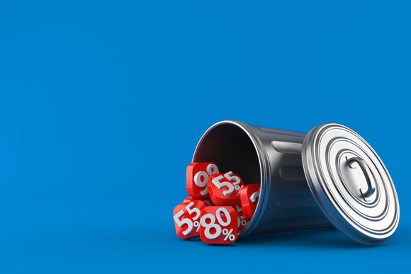 A garbage can tipped over with tiles with percent signs on them falling out.