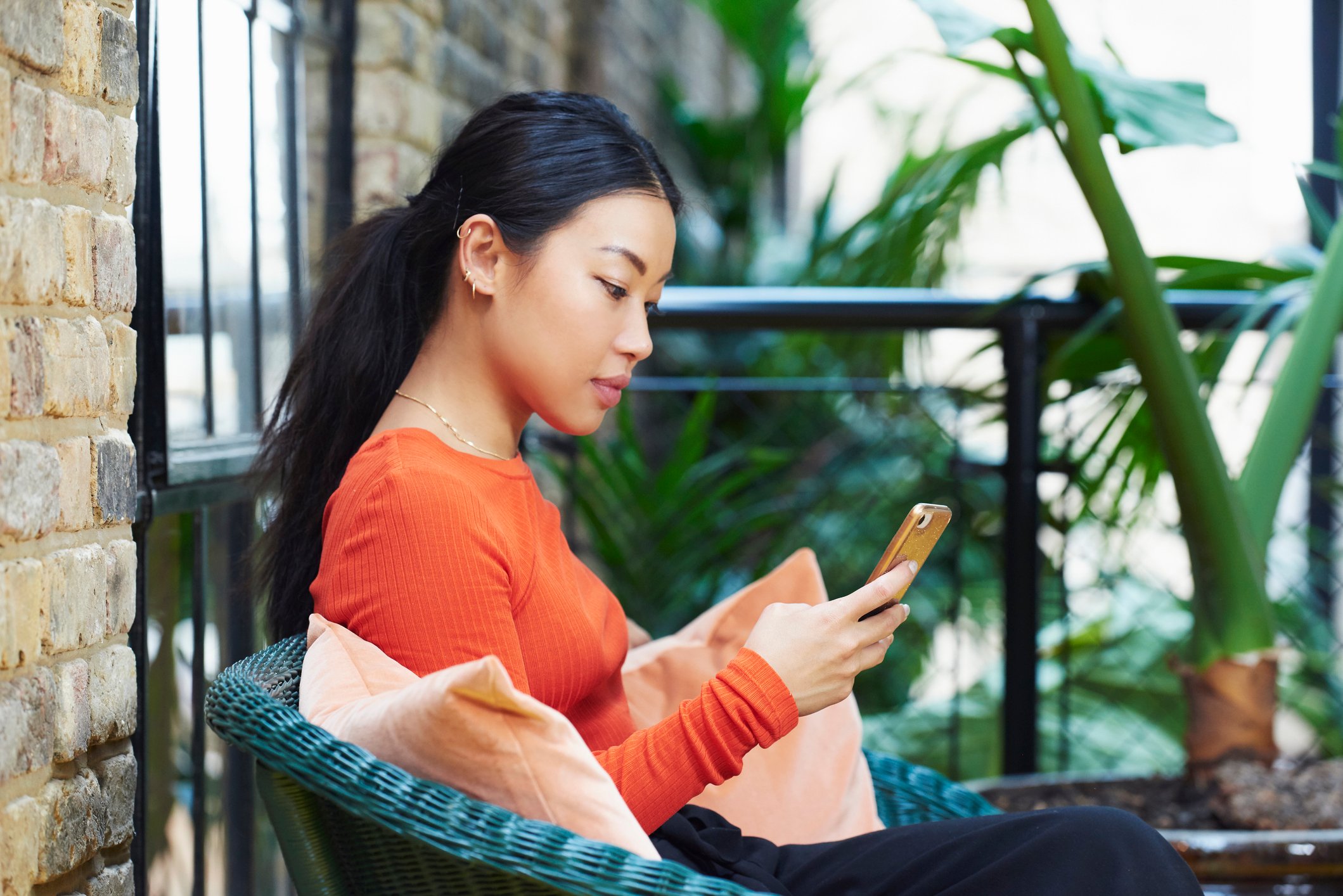 A person sits on a porch looking at their smartphone.