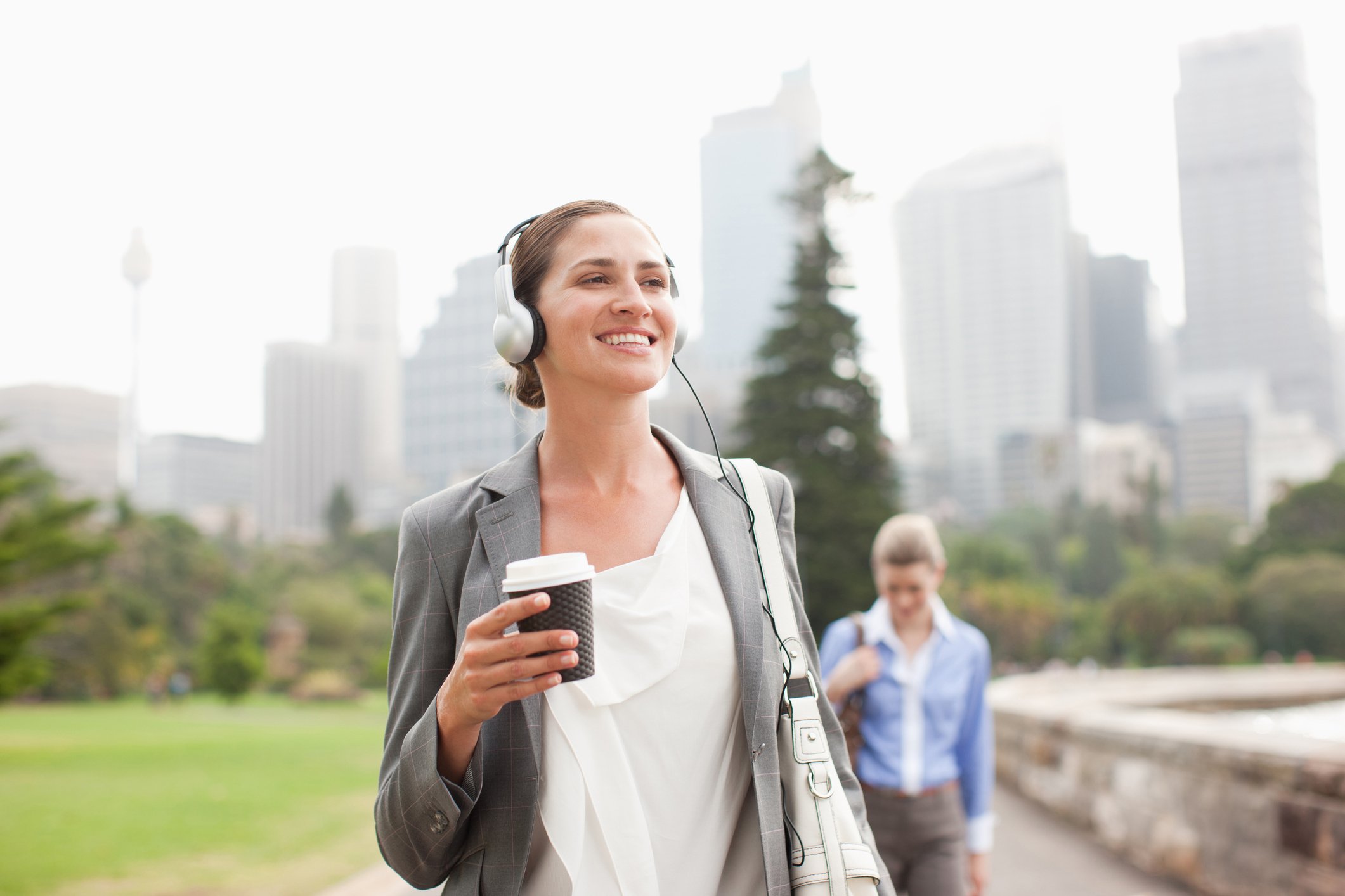 Person walking with headphones on and drinking coffee.