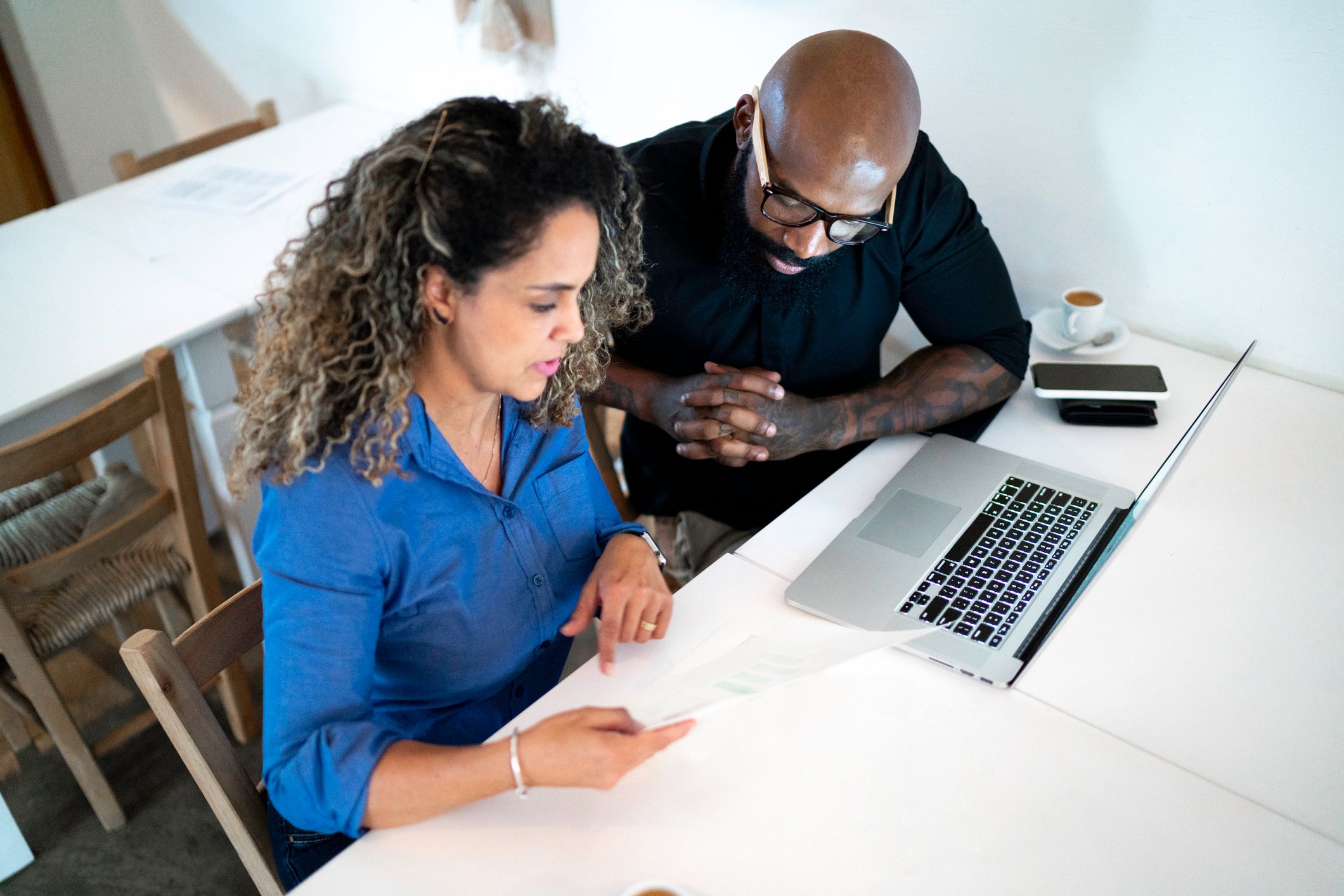 two coworkers ponder papers at desk