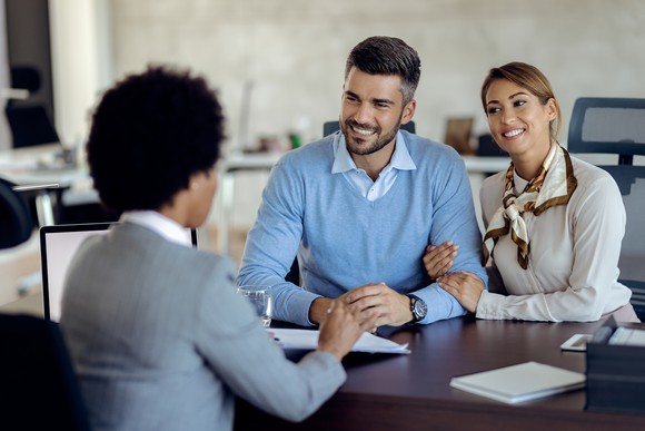 A banker meets with a couple at their desk.
