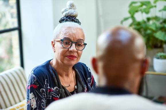 Two seniors seated at a table, having a discussion.