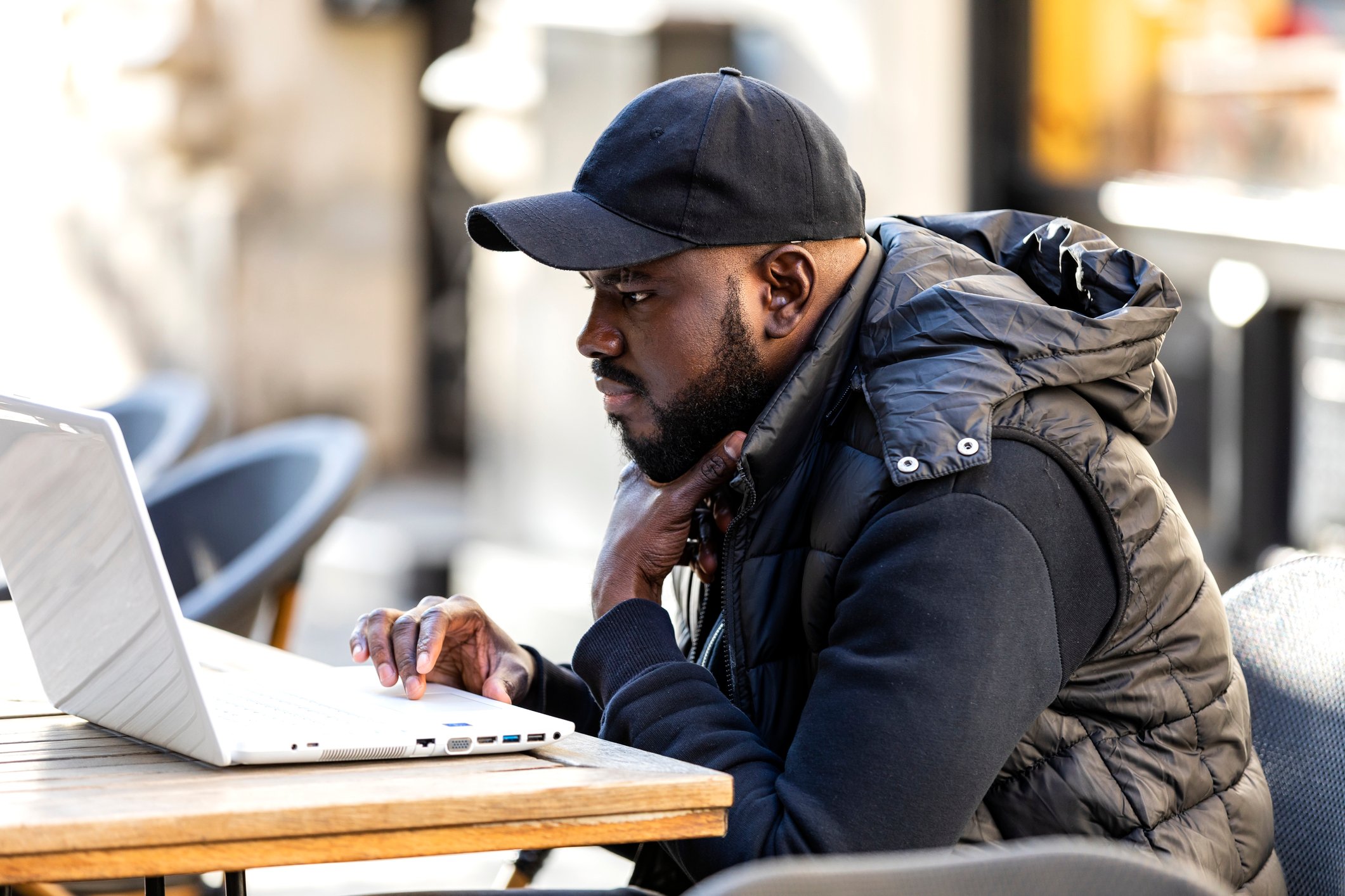 A person sits outside looking at a laptop.