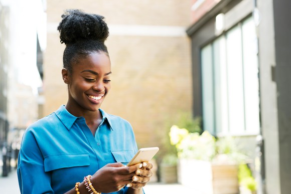 A woman smiling, looking at her phone.