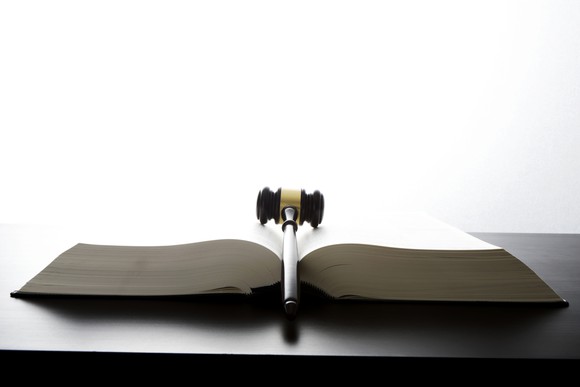 judges gavel on open law book sitting on wood table.