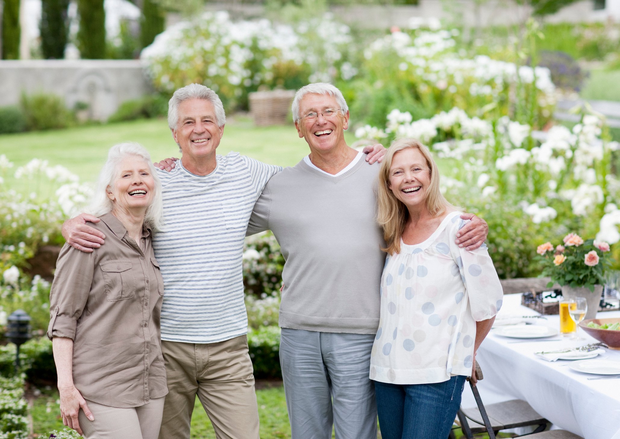 Four adults smile in a back yard.