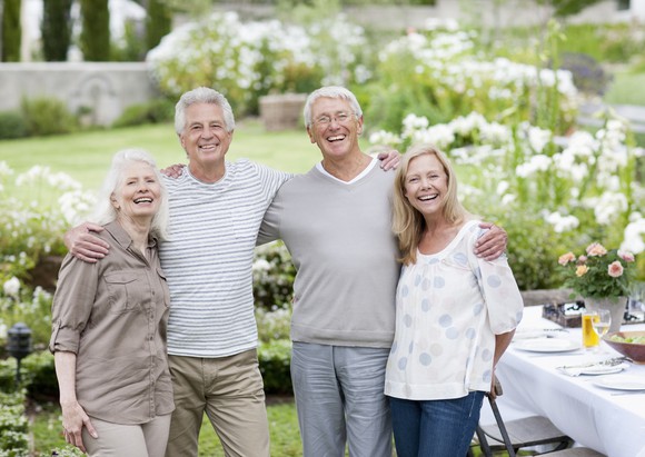 Four adults smile in a back yard.