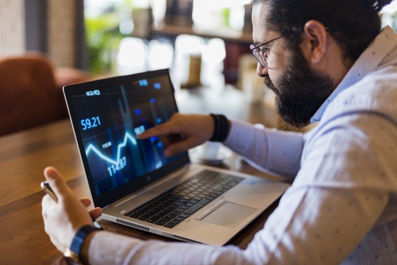 Adult male looking at a line chart on a laptop.
