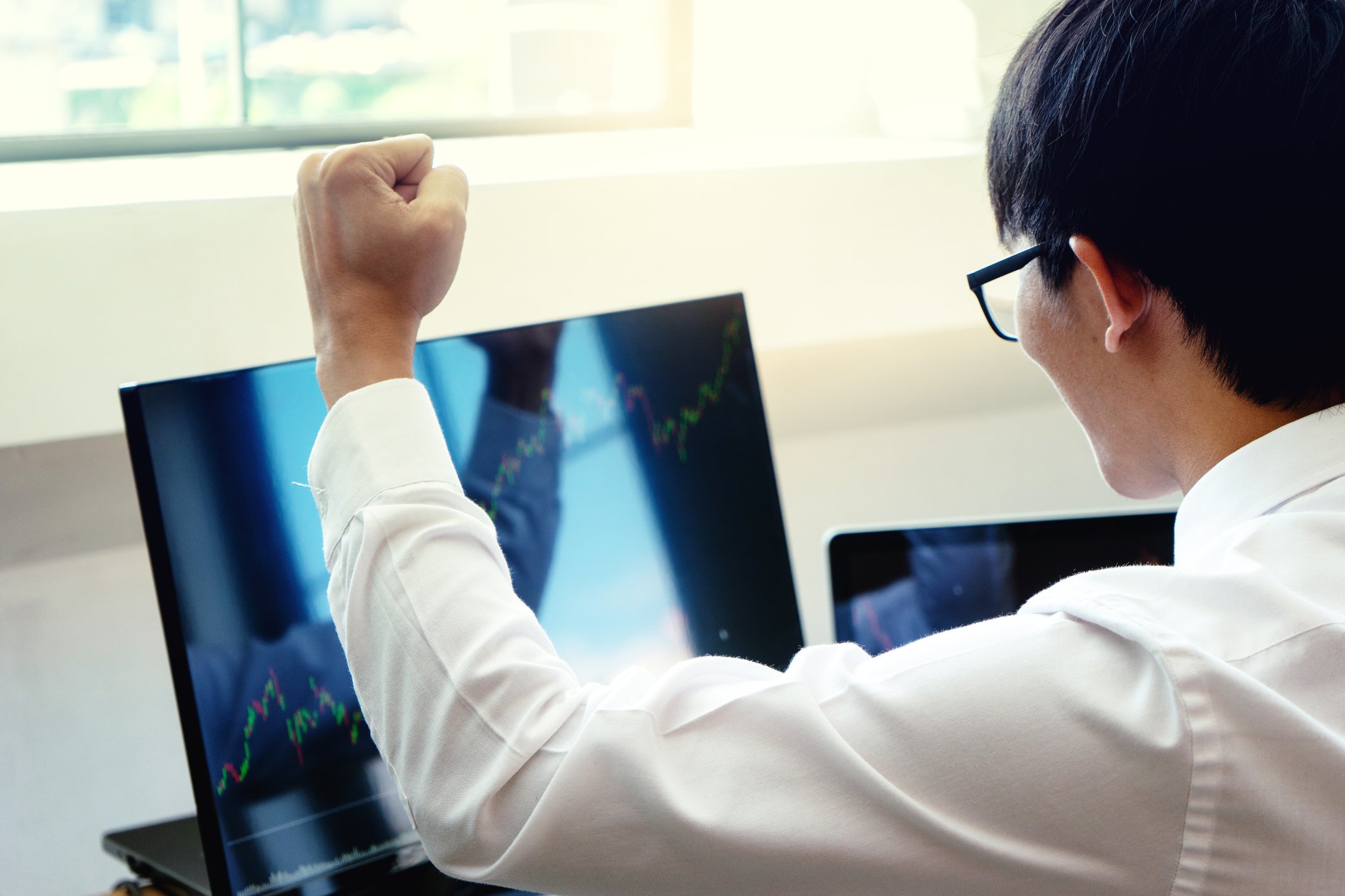 Stock trader cheering looking at rising chart.