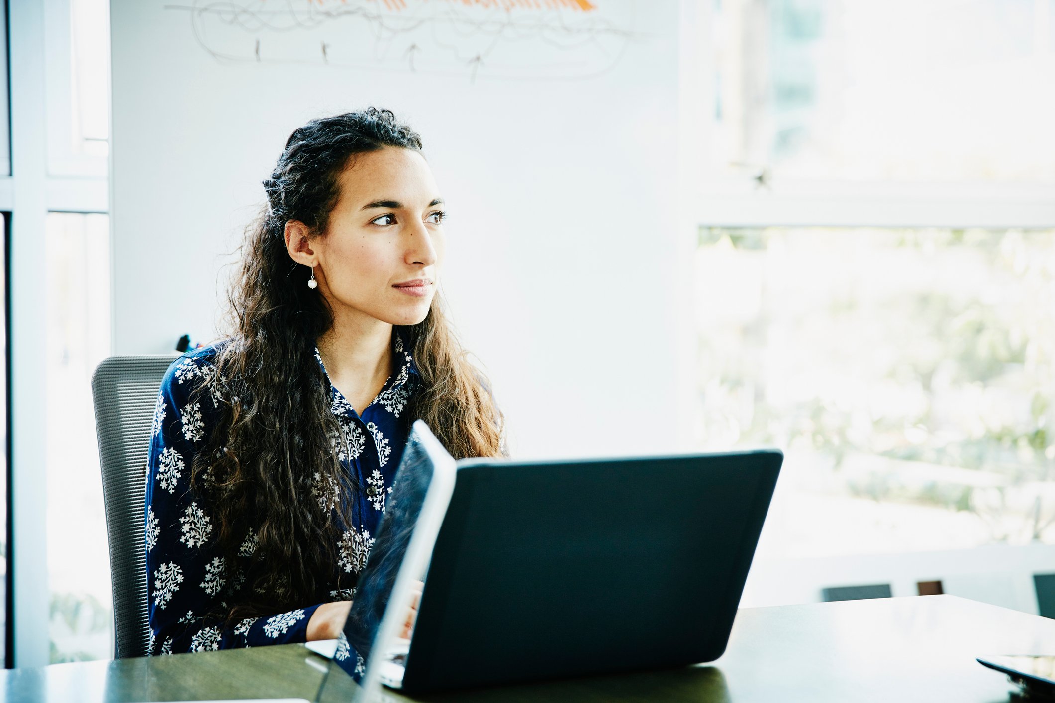 A person in front of a laptop looking away from the screen.