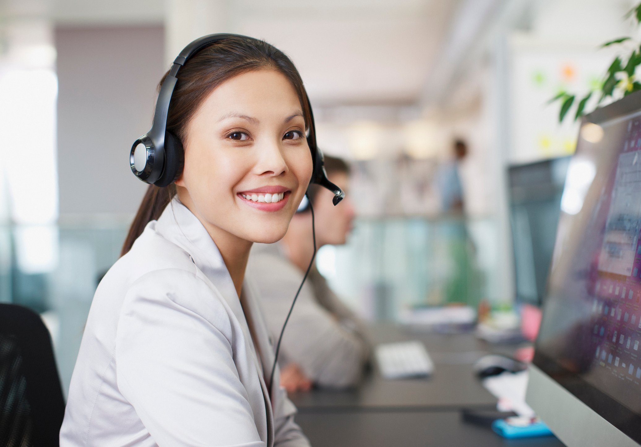 Worker smiles while wearing a headset and completing tasks online.