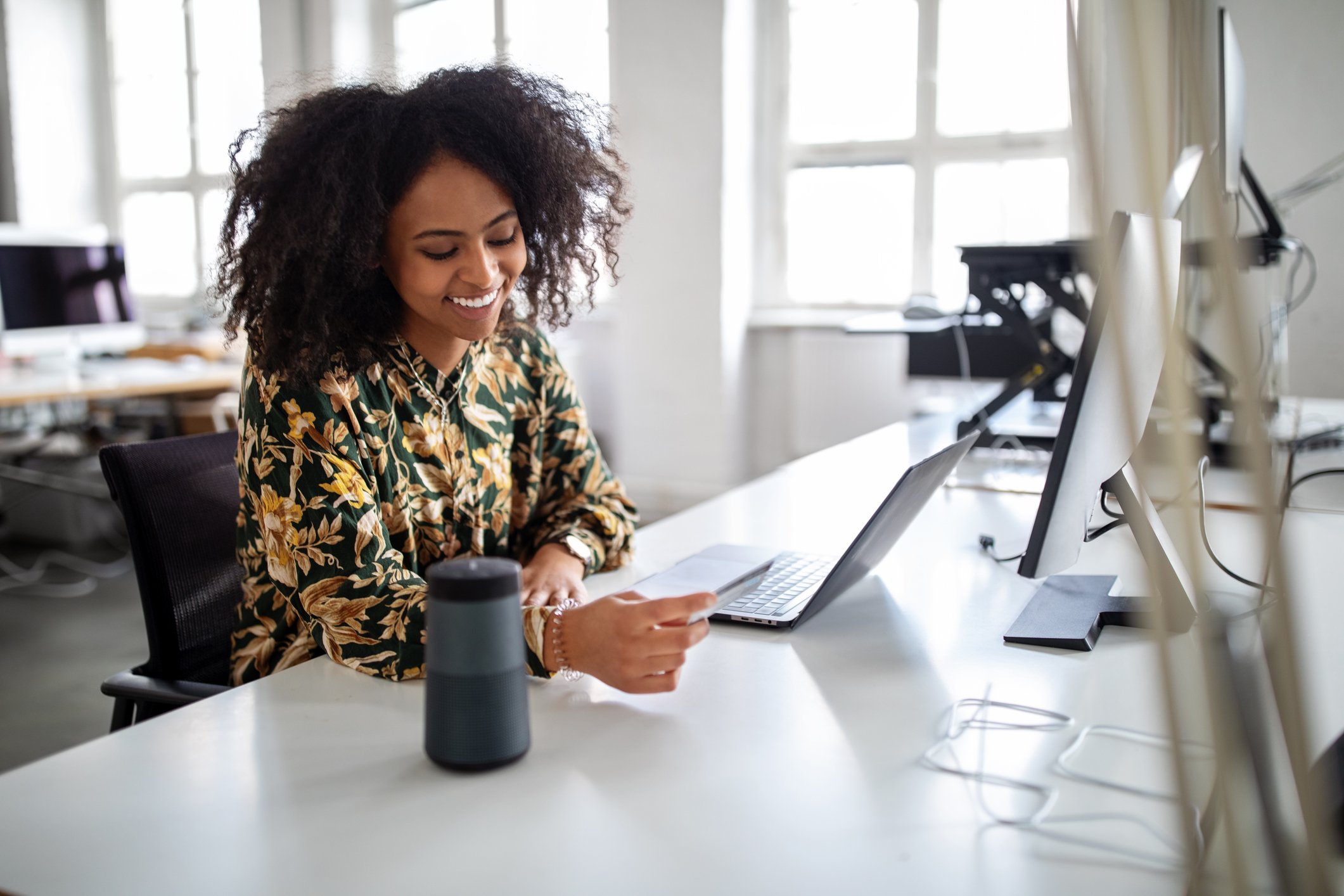 Person sitting at a desk in front of a laptop and holding a debit/credit card. 